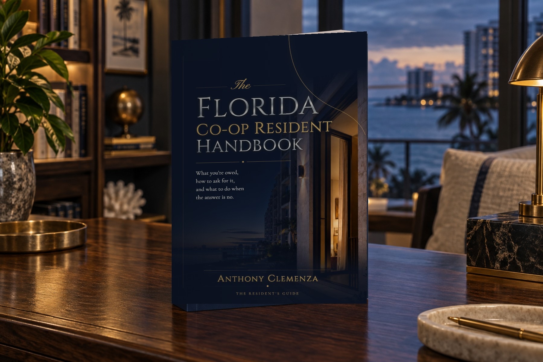 The Resident Handbook casewrap hardcover standing on a desk in an oceanfront residence at blue hour